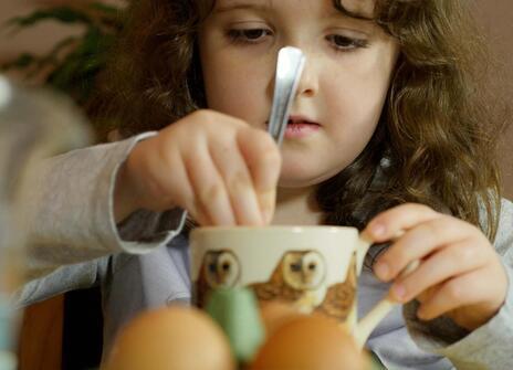 a girl stirs something in a cup with a spoon