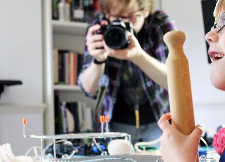 Small boy looking amazed at a science experiment while a photographer is capturing the moment in the background