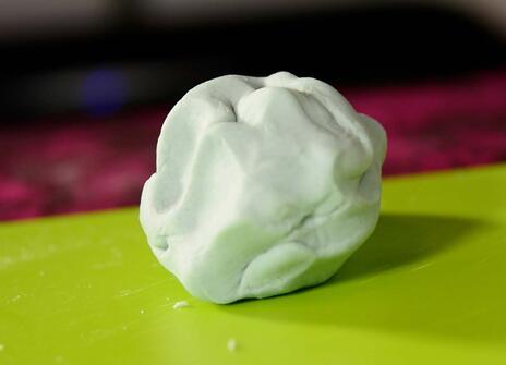a faintly blue coloured dough ball on a bright green chopping board