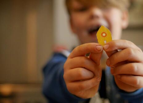 a small boy holds a small piece of cardboard shaped like a boat