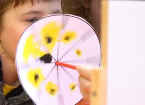 A boy peeks over a paper disc
