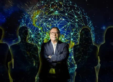 Jonathan van Tam with his arms crossed and a projection of a globe overlaying him, he's surrounded by silhouettes of six people