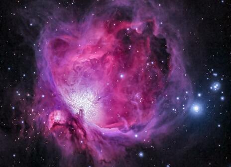 A pink and purple cloud of gas and dust, floating against the dark background of space. 