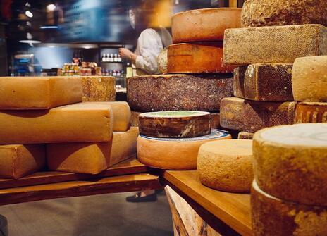 Lots of different cheese wheels are stacked on top of each other. 
