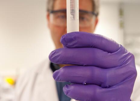 Person looking at tube filled with DNA