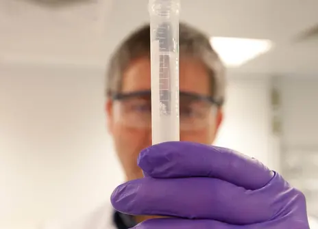 A person holds a tube filled with DNA
