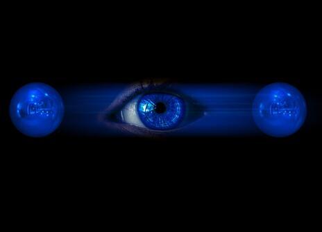 A picture of an eye in between two blue circles. It is an abstract picture of physics. 