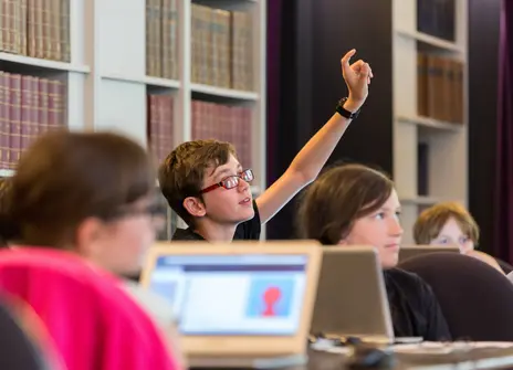 A child puts his hand up to ask a question during a coding workshop