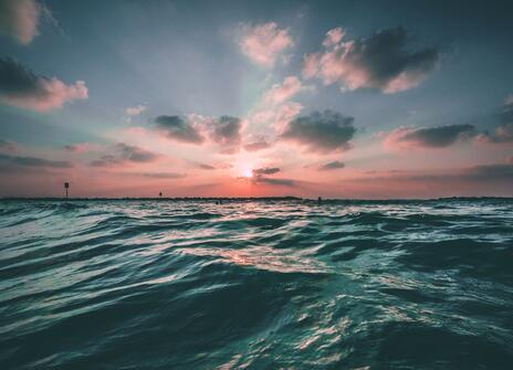 A view of the ocean, with a pink sunset just above the horizon.