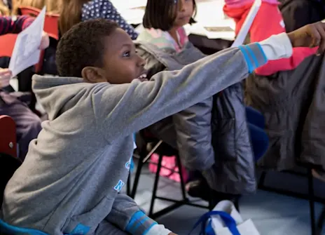 Young child in a grey jumper pointing ahead