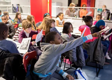 Room of enthusiastic children with their hands up 