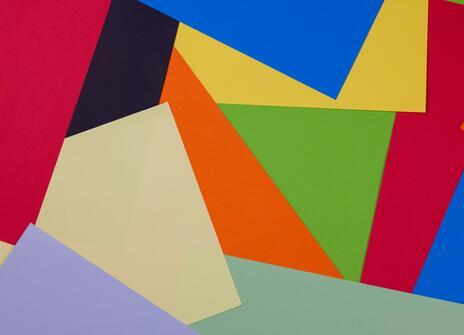 pieces of coloured paper fill the picture. Red, blue, green, orange, yellow, brown and purple. 