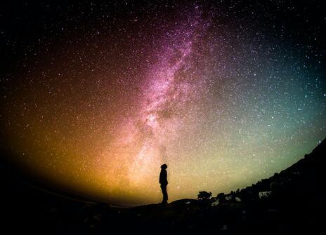A silhouette of a person in front of a starry night sky. 