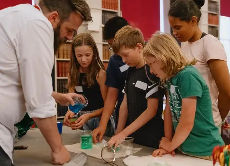 A man performing a science demonstration in front of five children