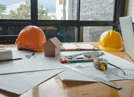 Hard hats and builidng plans scattered across a table
