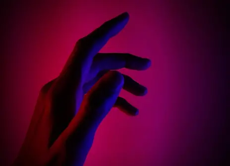 a shadow of a hand against a pink background