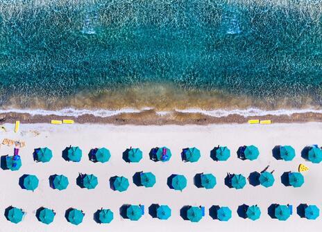 An aerial photo of umbrellas on a beach in a regular pattern