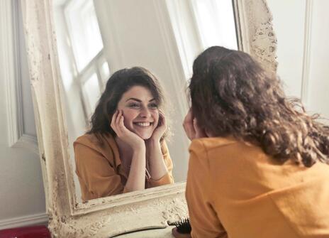 A women smiles into a mirror