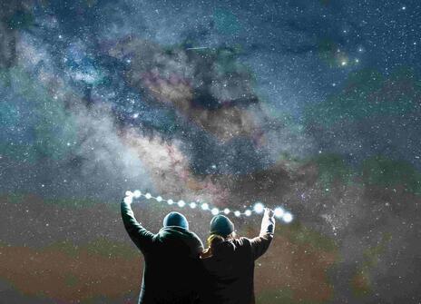 Two people observe the night sky with a ligh