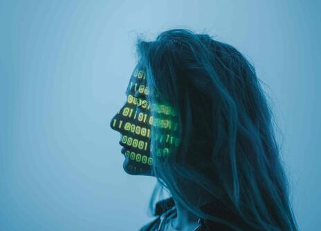 A women stands in front of projection of codes