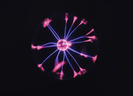 A plasma ball with a pink central ball of light and blue with blue sparks radiating out from it