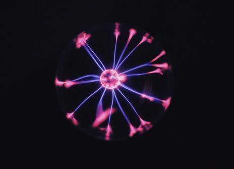 A plasma ball with a pink central ball of light and blue with blue sparks radiating out from it