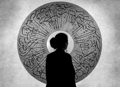 Silhouette of a woman against a round arabic ornament