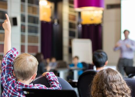 A child raising his hand in a classroom
