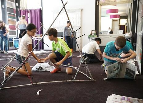 Students building structures with newspaper solid cane