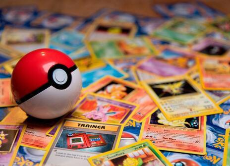 A red and white pokeball sits on top of lots of pokemon cards