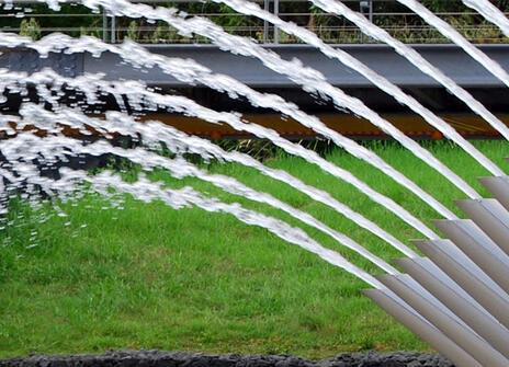water fountain with curved spouts where water comes out in symmetrical arcs from each spout